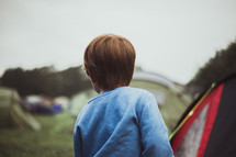 a boy standing near tents 