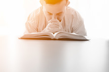 a man praying over an open Bible 