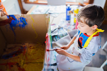 children painting a cardboard box 