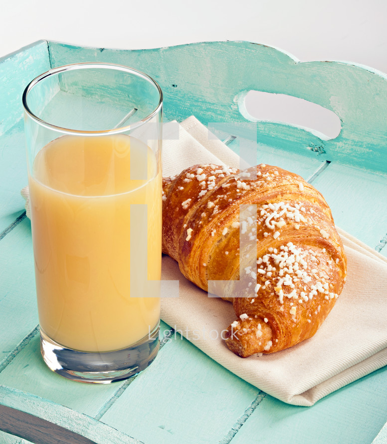 croissant and orange juice on a turquoise wood tray 