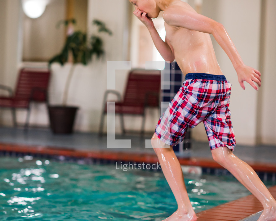 a boy jumping into an indoor pool 