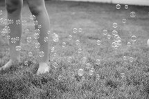child playing with bubbles in grass