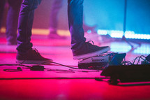 man with his foot on a guitar pedal on stage