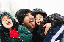 A father and his two sons playing in snow