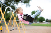 Little girl swinging high at the park 