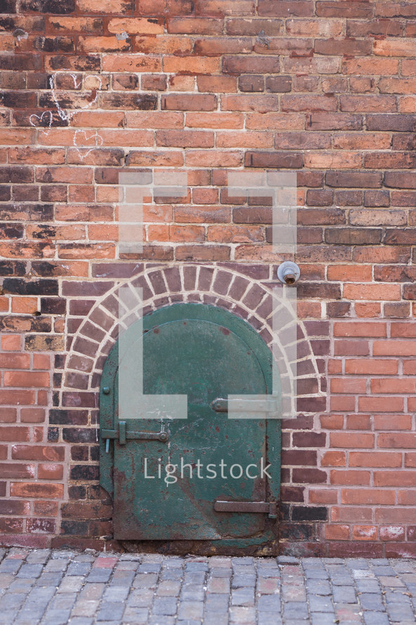 green metal door on a brick wall 