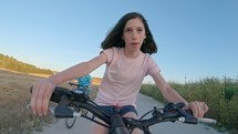 POV of a young girl enjoying a bicycle ride on the rural countryside.
