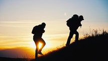 Silhouette of people walking with backpack and equipment climbing up mountain. Overcoming difficulties on way to success. Teamwork when climbing cliff. Natural beautiful landscape. Sporty lifestyle.