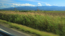 Panoramic shooting from the car in motion with green fields and mountains. Hand held 