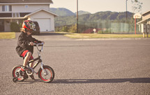boy child riding a bike with a helmet and training wheels