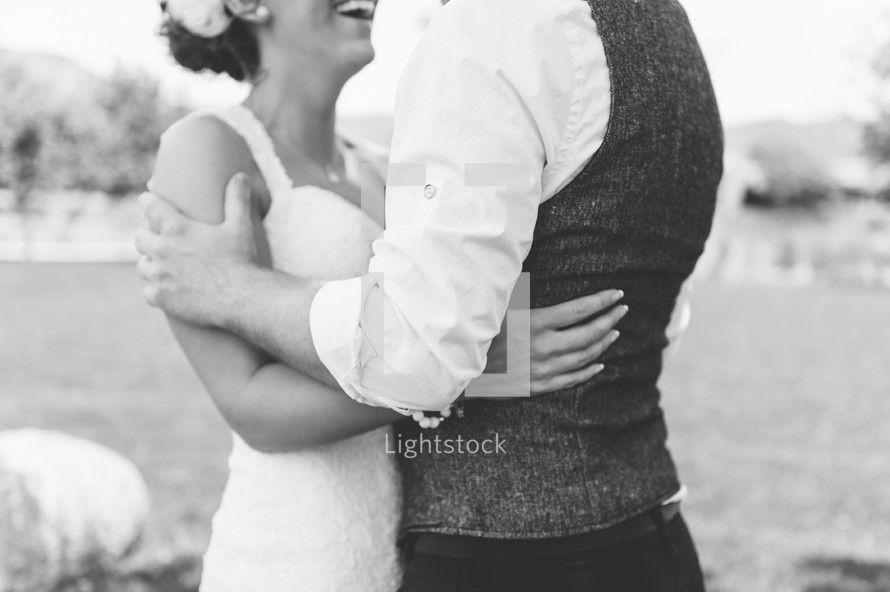 Bride and groom standing together holding each other outdoors