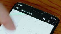 Close up of finger browsing through a smartphone calendar