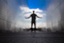 blurry silhouette of a man with outstretched arms 