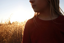 girl standing in a field of brown grasses 