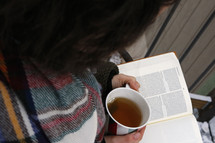 a woman reading a Bible with tea 