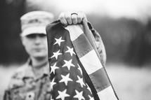 soldier in a field holding an American flag 