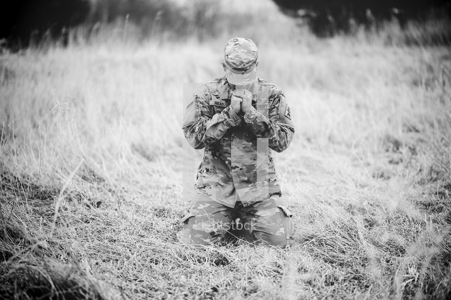 soldier kneeling in a field in prayer 