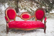 a red couch in the snow outdoors 