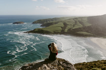a woman taking in the views sitting on the edge of a cliff in New Zealand 