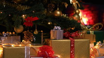Christmas gifts near Christmas tree in atmospheric lights in front of fireplace. Dolly shot 