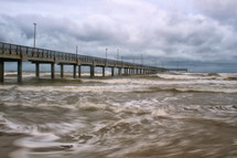 Ocean waves surrounding a pier.