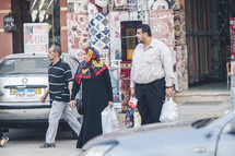 husband and wife walking on the streets of Egypt carrying shopping bags 