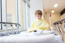 a boy child in a hospital gown in a hospital bed 