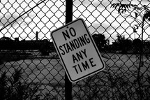 No standing any time sign on a chain link fence 
