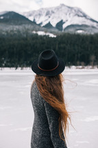 a woman with long red hair wearing a hat outdoors in the snow 