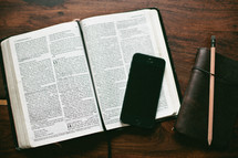 open Bible, cellphone, and journal 