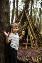 a child with a teepee of sticks in the woods 