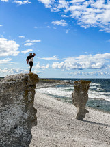 a man standing on a rocky cliff along a shore 