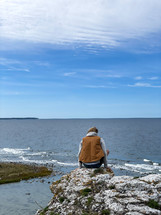 a man sitting on a rocky shore 