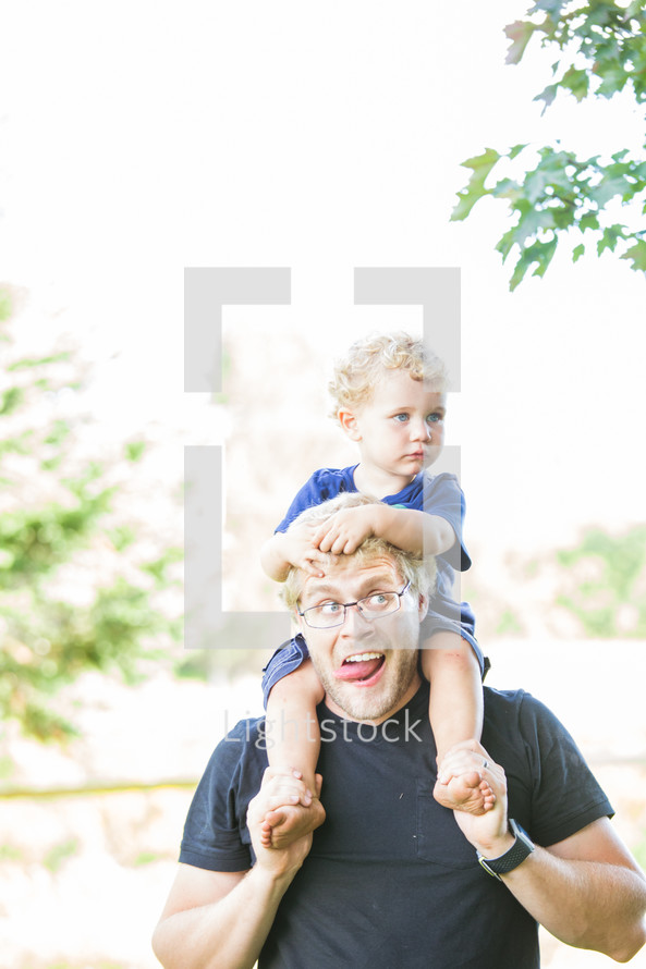 father carrying his toddler son on his shoulders 