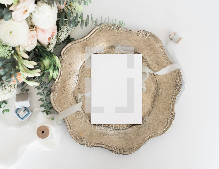 stationary on a silver tray, spool of ribbon, and bouquet for wedding invitations 