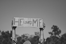 Boy holding "He Loves Me" sign