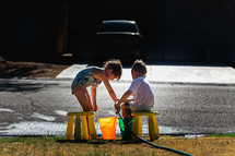 kids filling buckets with water from a hose 