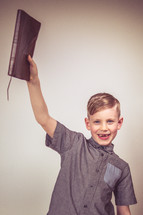 young boy holding up a Bible 