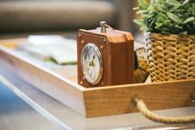 clock and house plant in a wooden tray 