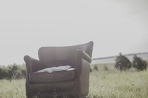 a Bible in a leather chair in a field 