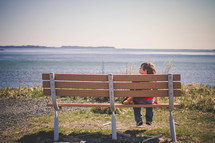 boy child sitting on a park bench 