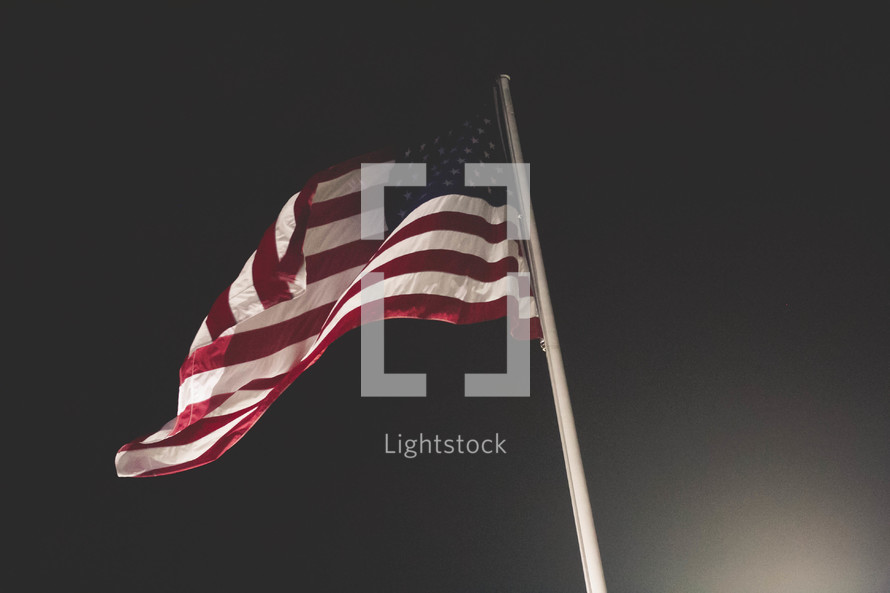American flag on a flagpole at night 
