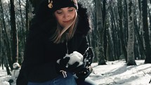 Girl prepares snowball in the forest 