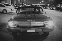A vintage car shines its headlights 