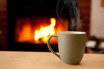 Steaming coffee cup and fireplace