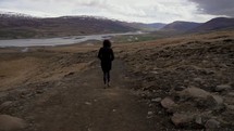 a woman walking on a dirt path 