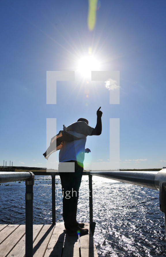man standing at the edge of a dock with his finger pointing up