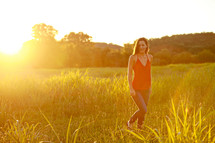 Woman in grass field at sunset