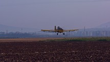 Crop duster spraying chemicals over a cotton field - slow motion