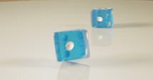 Slow motion macro shot of dice falling and rolling on reflective surface